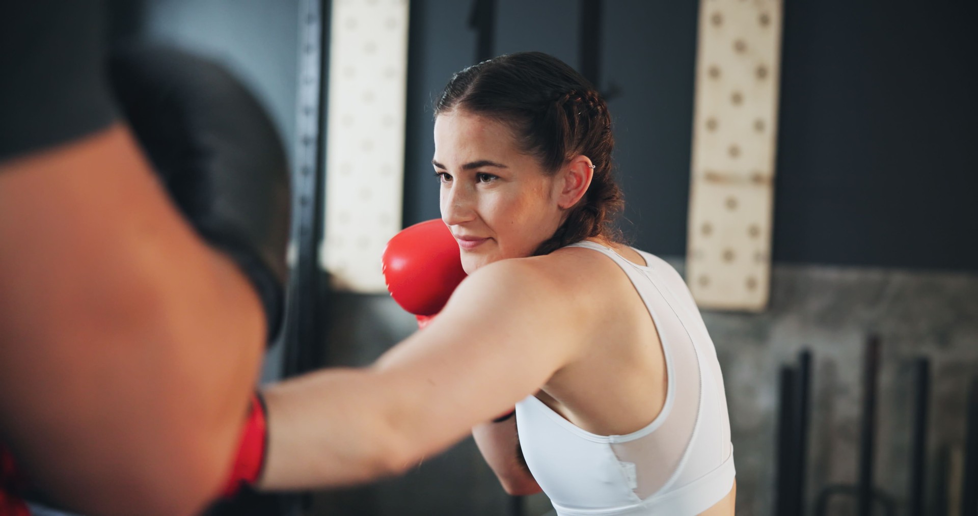 Fitness, mujer y boxeo en gimnasio para entrenamiento, defensa personal y ejercicio con entrenador personal. Entrenamiento de potencia, puñetazo y atleta femenina con equipo para el deporte, el aprendizaje y la lucha con trabajo duro